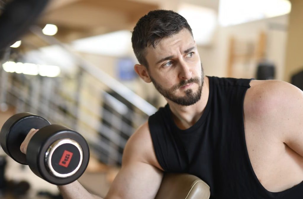 A determined man lifting a dumbbell indoors, showcasing strength and fitness.