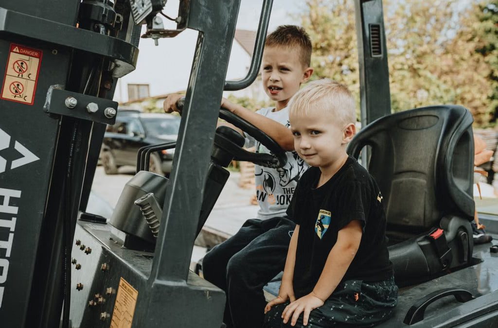 Two young boys explore a stationary vehicle outdoors, embodying play and curiosity.